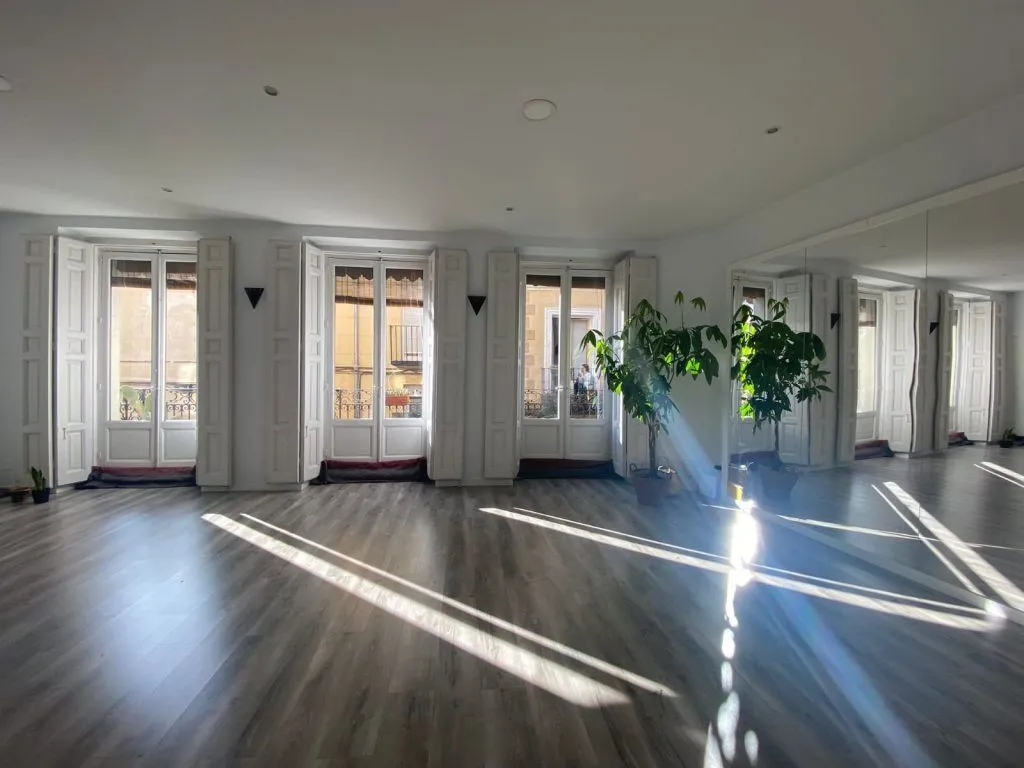 Madera Yoga Estudio con ventanales, plantas y pared de espejo