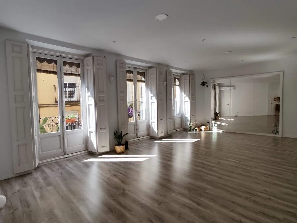 Sala luminosa de Madera Yoga Estudio con suelo de madera y grandes ventanales
